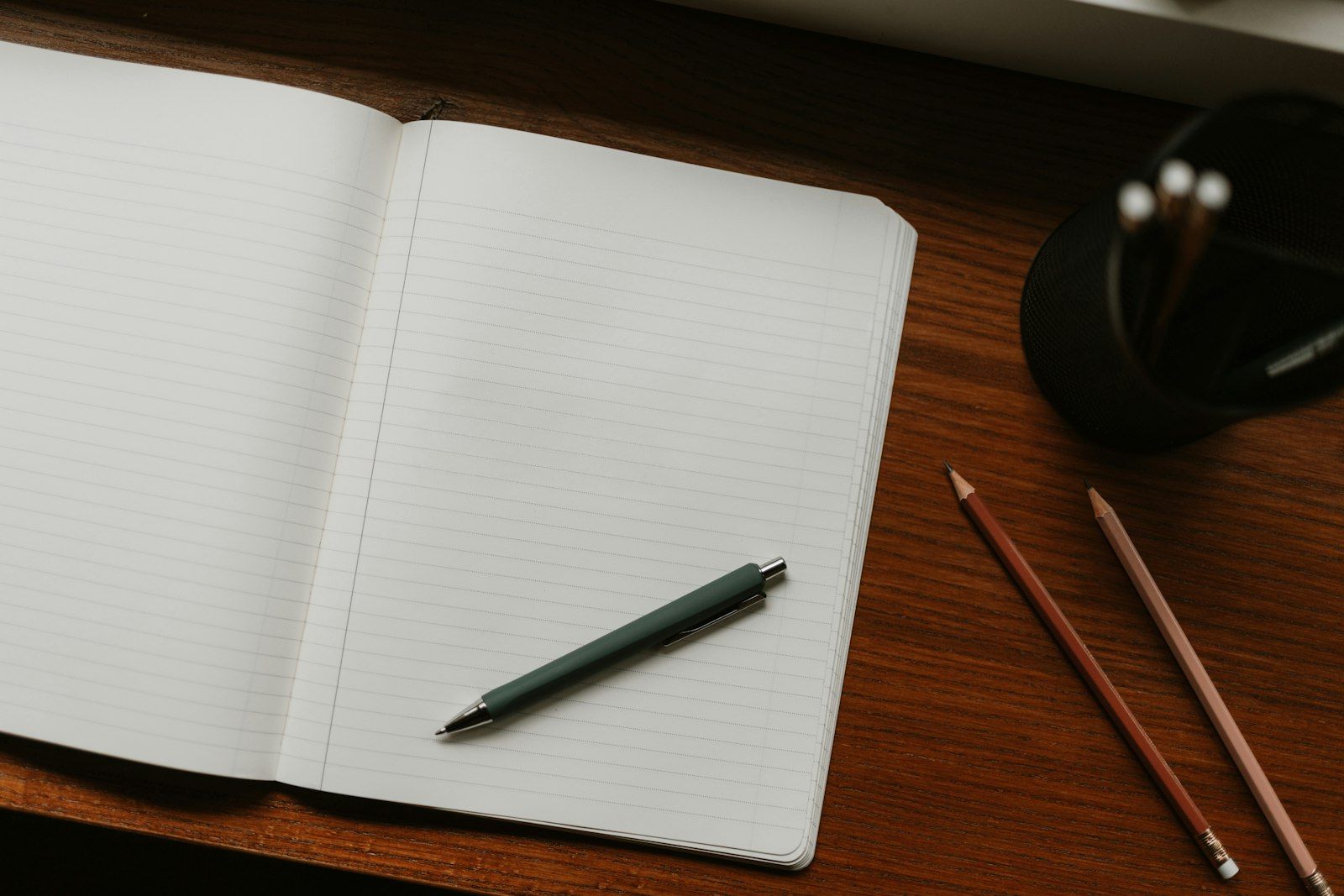 Quaderno aperto con penna e matite sulla scrivania, per scrivere la richiesta al geometra